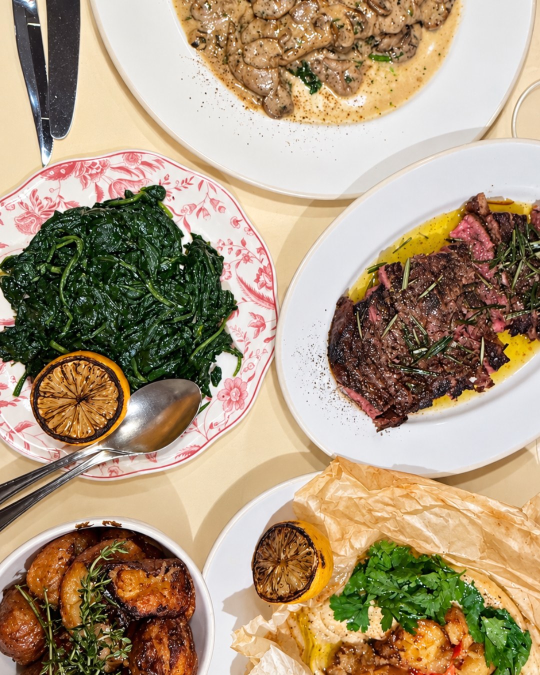 Overhead spread of veal scallopini, sirloin, spinach, potatoes and branzino