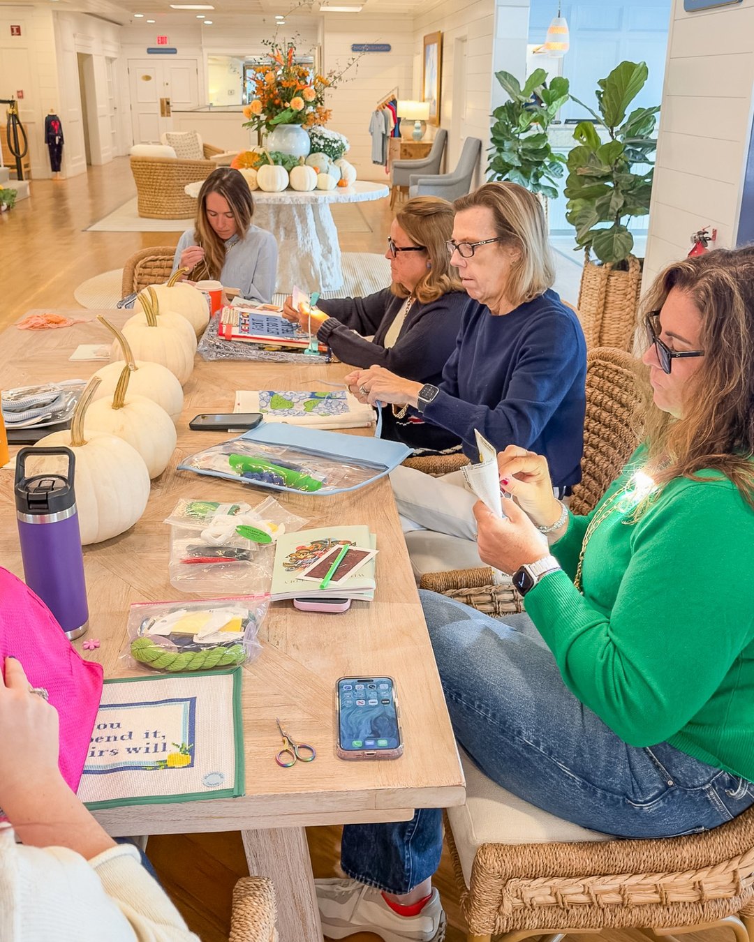 Retreat guests stitching needlepoint canvases at a long table in the Nantucket Inn lobby